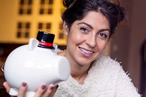 Young woman with braces holding white ceramic piggybank