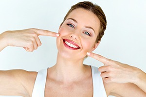 Woman pointing to smile with porcelain veneers