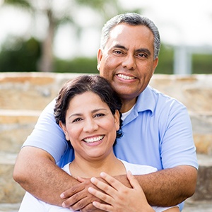 Man and woman smiling after dental crown and fixed bridge restorations