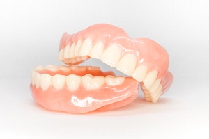 Top and bottom full dentures against neutral background