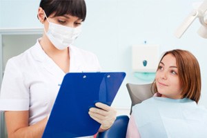 Dentist holding clipboard, standing next to patient