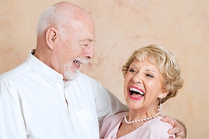 Older man and woman laughing together after dental implant supported tooth replacement