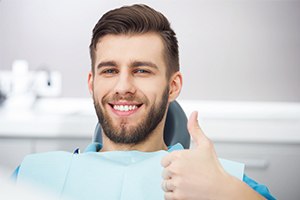Smiling young man giving thumbs up after wisdom tooth extraction