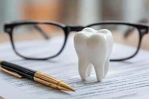 Glasses and tooth model on top of insurance document