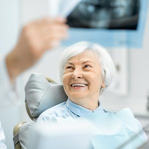 Older man talking to dental team member at reception desk