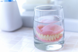 Dentures in glass of water on bathroom countertop