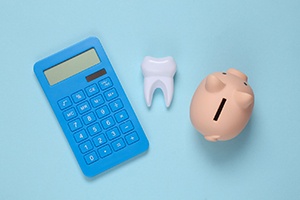 Piggybank, tooth, and calculator arranged against blue background