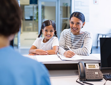 Mother and daughter checking in at dental office reception desk