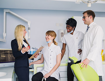 Smiling dental team talking to female patient in business attire