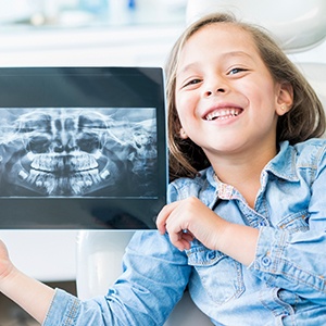 Little girl holding up her dental x-rays on a tablet computer