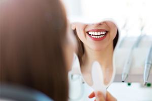 Woman looking in mirror after smile makeover