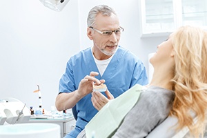 Dentist showing patient a dental bridge model