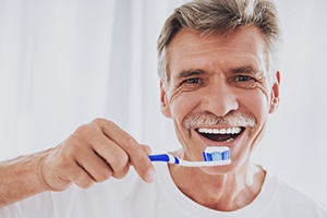 Man brushing teeth after dental restoration