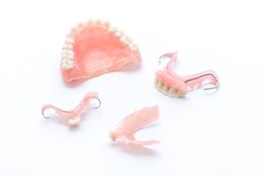 Full denture and partial dentures against neutral background
