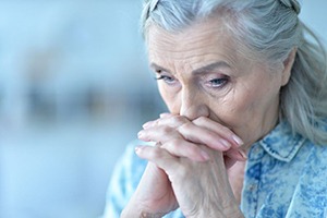 Sad senior woman holding her hands near her mouth