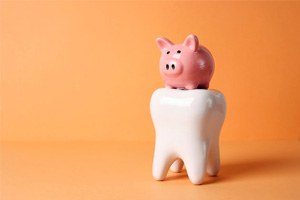 Piggy bank sitting on top of tooth model