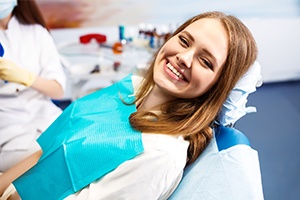 Woman in dental chair smiling after tooth extraction