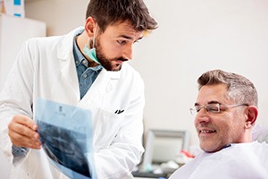 Dentist holding X-ray, explaining treatment recommendation
