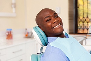 Smiling male patient in dental chair, waiting for tooth-colored filling