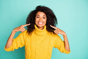 Woman pointing at smile, enjoying benefits of tooth-colored fillings