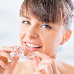 Smiling woman holding tray for Invisalign® in East Hartford