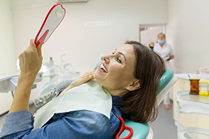 Dental patient using mirror to admire metal-free restorations