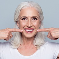 Woman pointing to her smile after periodontal laser treatment