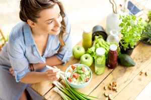 Smiling woman enjoying colorful salad at picnic table