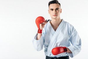 Young man dressed in martial arts gear, holding mouthguard