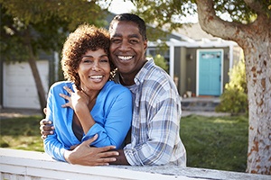 Man and woman smiling outdoors after restorative dentistry treatment