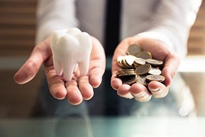 Tooth model in one hand, money in the other