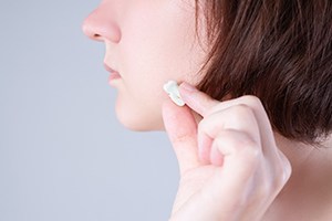 Woman holding extracted tooth next to her face