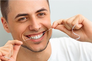 Man flossing his teeth after same day dental crown restoration