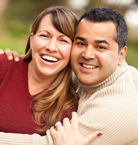 Man and woman smiling and embracing outdoors