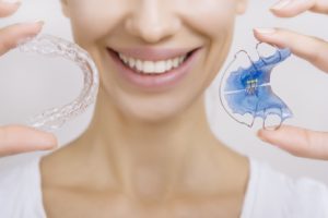 Woman with straight teeth holding two removable retainers