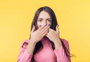 Woman hiding mouth, wondering if she should see an emergency dentist for facial swelling in East Hartford