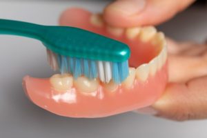 Close-up of toothbrush removing denture stains in East Hartford