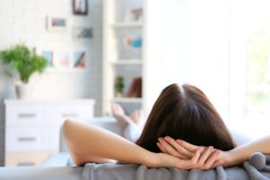 Woman relaxing on sofa while recovering from root canal therapy