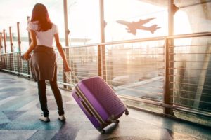 Woman walking through airport, dragging suitcase