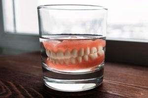 Dentures in cup of water next to window