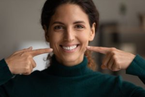 Happy, smiling woman pointing at her teeth