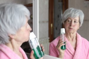 Older woman rinsing her mouth to freshen her breath