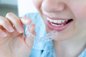Woman holding Invisalign aligner close to her teeth