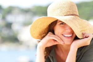 Smiling woman with perfect teeth, wearing a sun hat 
